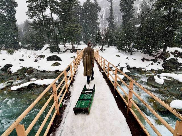 May 10 man-walking-snowy-bridge_89913_990x742